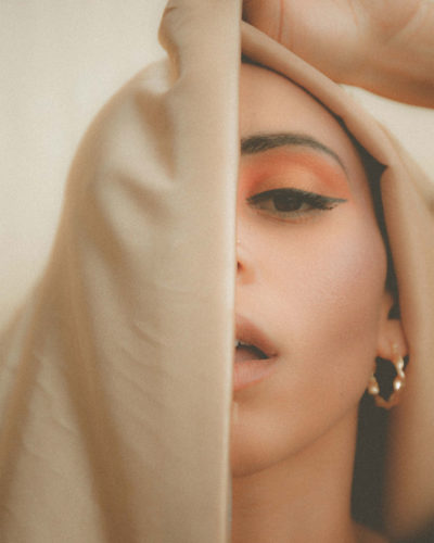 A young woman's face partially obscured by a veil